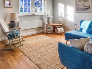 A living room with a rocking chair, blue sofa, and a wooden floor. - 2 bedroom accommodation in Garlieston (Garlieston)