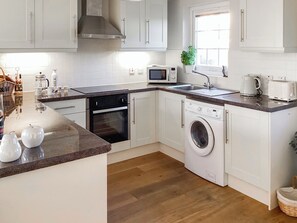 A modern kitchen with white cabinets, a microwave, a washing machine, and a sink. - 2 bedroom accommodation in Garlieston (Garlieston)