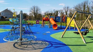 Ein Spielplatz mit Klettergerüst, Rutsche und Schaukeln.