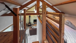 Een slaapkamer in een loft met een houten trap, een bed, een bank en een open haard.