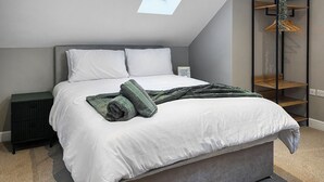 A bedroom with a skylight, a bed with white linens, a dark nightstand, and a wooden shelf unit. - 2 bedroom accommodation in Barnard Castle (Barnard Castle)