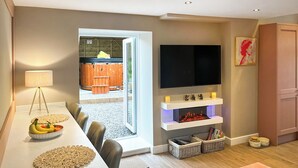 A modern living room with a dining area, a fireplace, a TV mounted on the wall, and a view to the outside. - 2 bedroom accommodation in Barnard Castle (Barnard Castle)