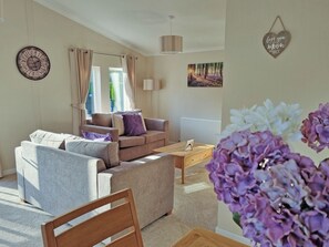 A living room with a sofa, armchairs, a coffee table, and a wooden chair. There is a clock on the wall and a framed picture above the sofa. - 2 bedroom accommodation in Little Weighton, near Beverley (Little Weighton, near Beverly)