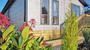 Una casa de dos pisos con fachada de madera, ventanas grandes y un porche de madera.