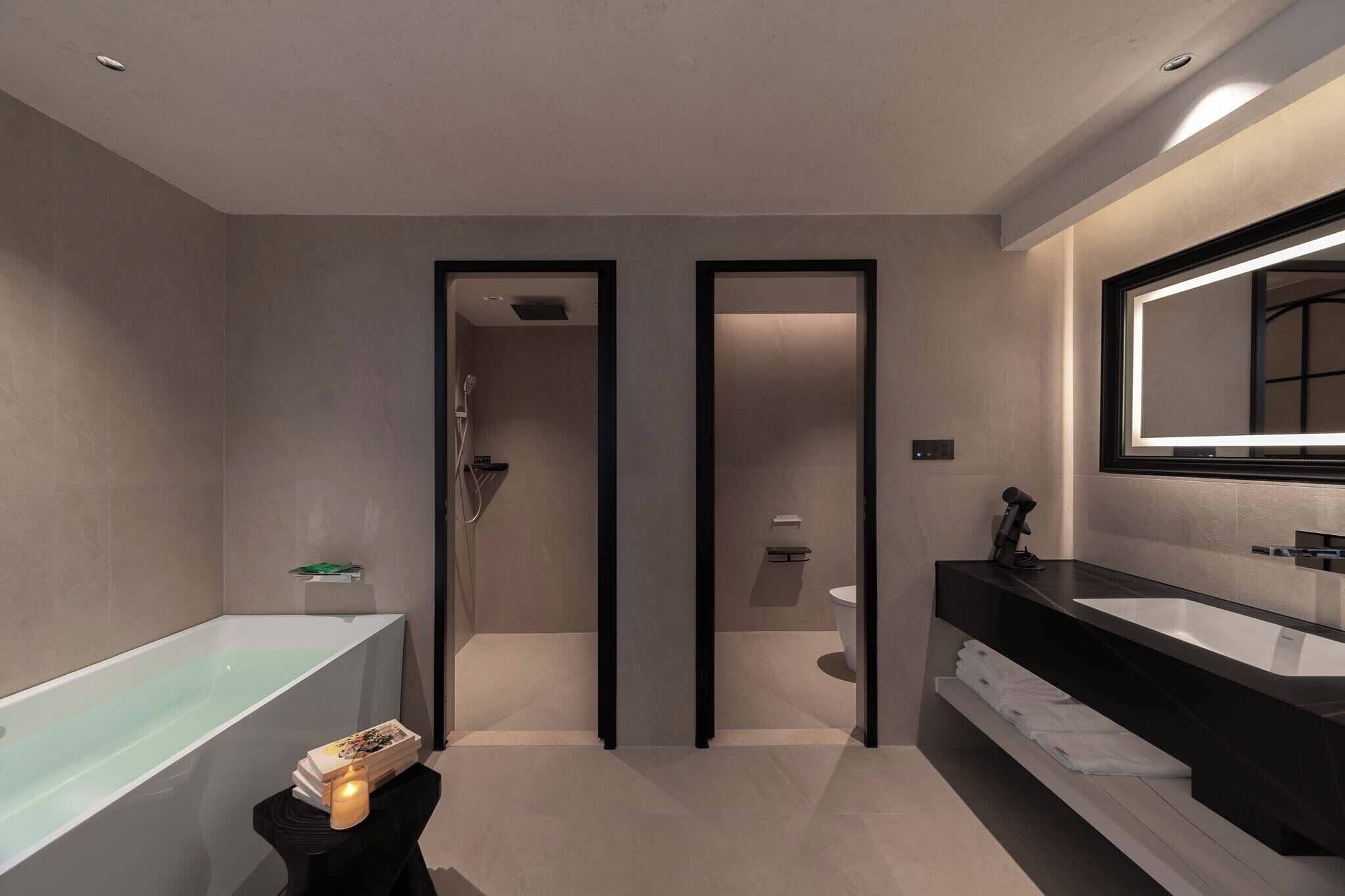 A modern bathroom with a large bathtub, a separate shower area, and a vanity with a large mirror.
