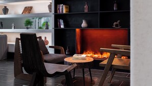 Un interior moderno con chimenea, muebles de madera oscura y una estantería con diversos objetos decorativos.
