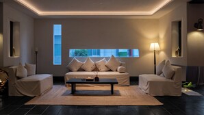 Una sala de estar moderna con un conjunto de sofás, una mesa de centro y un ventanal que deja entrar luz natural.