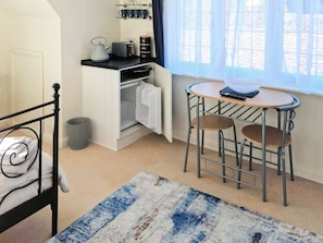 A compact room with a bed, a small kitchenette, a dining area with a table and chairs, and a window with curtains. - 1 bedroom accommodation in Bognor Regis, near Chichester (Bognor Regis)