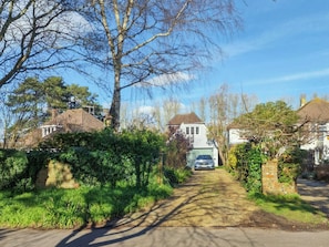 Une rue résidentielle bordée de maisons, avec une voiture garée devant l’une d’elles, et un ciel dégagé.