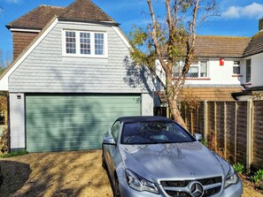A two-story house with a garage, a tree in front, and a parked car. - 1 bedroom accommodation in Bognor Regis, near Chichester (Bognor Regis)