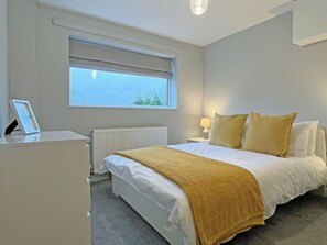 A bedroom with a bed, bedside table, lamp, window, radiator, and a picture frame. - UK51148 - Clay Hall Farmhouse (Scaling Dam, near Staithes)