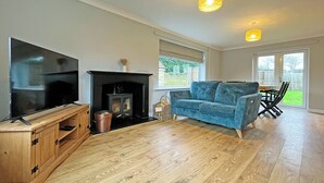 Ein Wohnzimmer mit Fernseher, Kamin, Sofa und Holzboden.