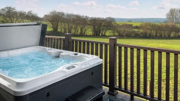 A hot tub on a deck with a view of a grassy field and trees. - 2 bedroom accommodation in Chadwick, near Worcester (Chadwick, near Worcester)