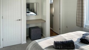 A bedroom with a bed, a bedside table, a mirror, a wardrobe, and a bathroom door. - 2 bedroom accommodation in Chadwick, near Worcester (Chadwick, near Worcester)