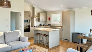 A modern kitchen with a central island, a dining area with a table and chairs, and a living room with a sofa and coffee table. - 2 bedroom accommodation in Chadwick, near Worcester (Chadwick, near Worcester)
