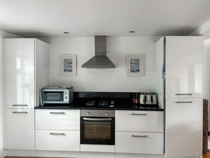 A modern kitchen with white cabinets, a microwave, a toaster, an oven, and a gas stove. - 1 Richmond Place - UK51155 (St Ives)