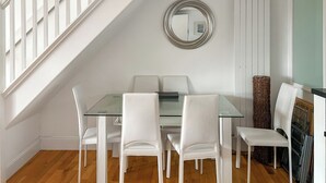 En matplats med ett glasbord, vita stolar, en spegel och en trappa.