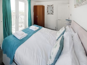 A hotel room with a bed, a wardrobe, a mirror, and a window with curtains. - 1 Richmond Place - UK51155 (St Ives)