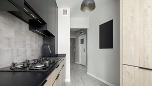 Een moderne keuken met een zwart aanrecht, roestvrijstalen apparatuur en houten kastfronten in een lichte houttint.