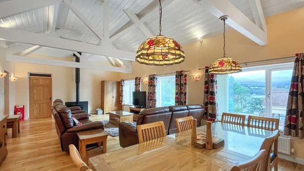Amplia sala de estar con una mesa de comedor de madera, sofás de cuero y un ventanal con vistas.