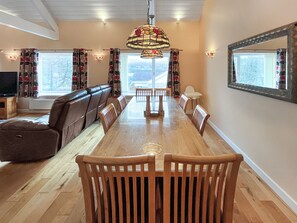 A dining area with a long table, chairs, a sofa, and a television. - 4 bedroom accommodation in Menai Bridge (Menai Bridge)