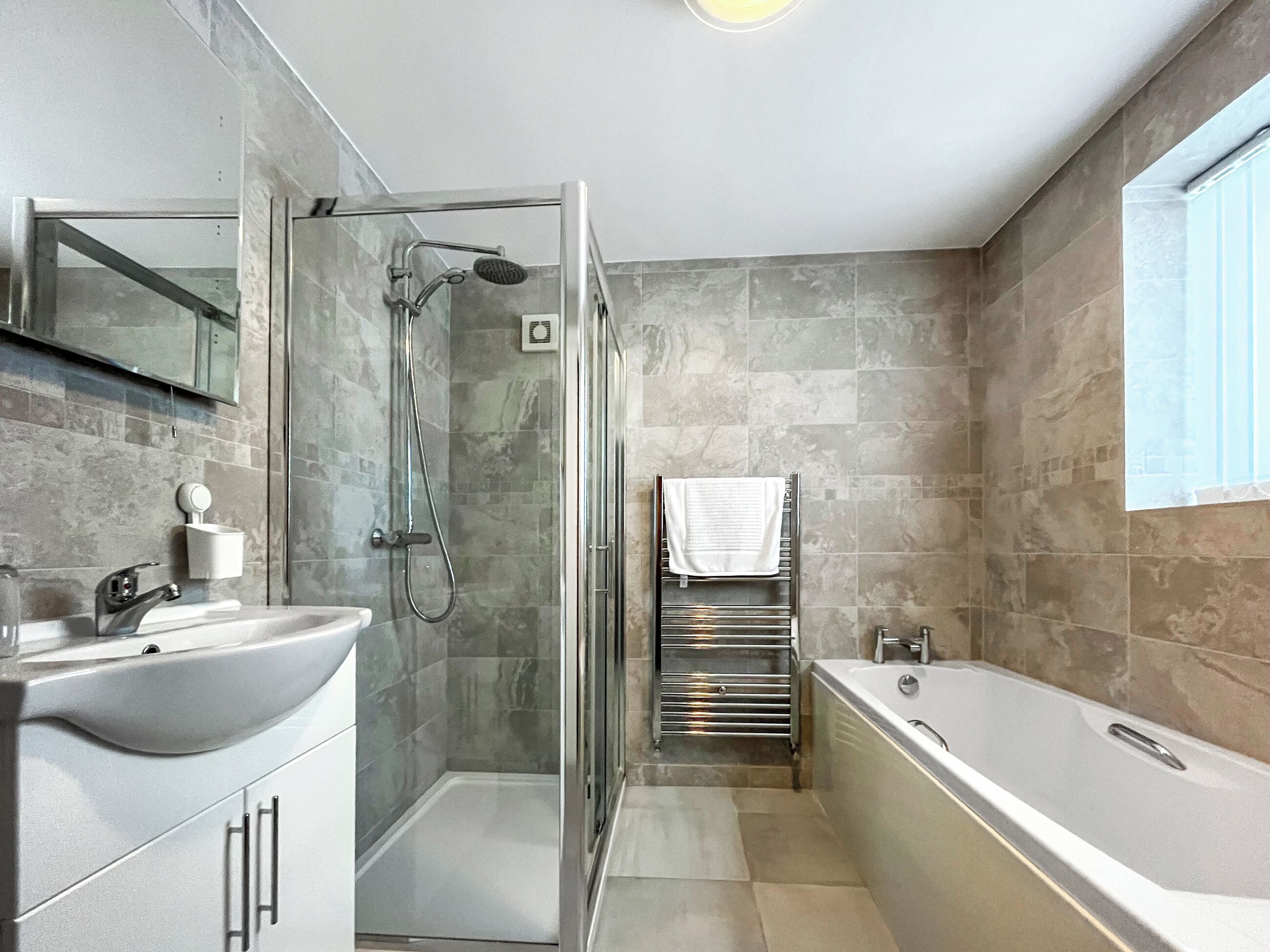 A modern bathroom with a glass-enclosed shower, a freestanding bathtub, and a vanity with a sink.