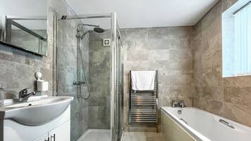 A modern bathroom with a glass-enclosed shower, a freestanding bathtub, and a vanity with a sink.