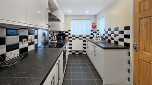 Una cocina moderna con baldosas blancas y negras en damero, electrodomésticos de acero inoxidable y una puerta de madera.