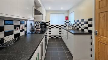 A modern kitchen with black and white checkered tiles, stainless steel appliances, and a wooden door.