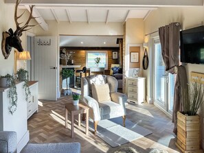 A cozy living room with a fireplace, a television, and a dining area with a wooden table and chairs.