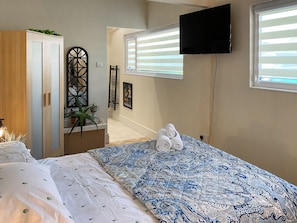 Um quarto com uma cama, um guarda-roupa, uma televisão e uma janela.