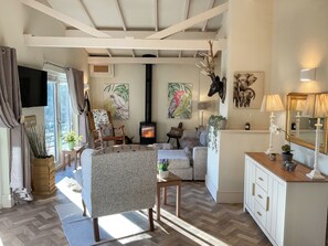 A cozy living room with a fireplace, comfortable seating, and decorative wall art.
