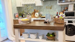 Una cocina con gabinetes blancos, una campana de acero inoxidable, un microondas y un horno empotrado.
