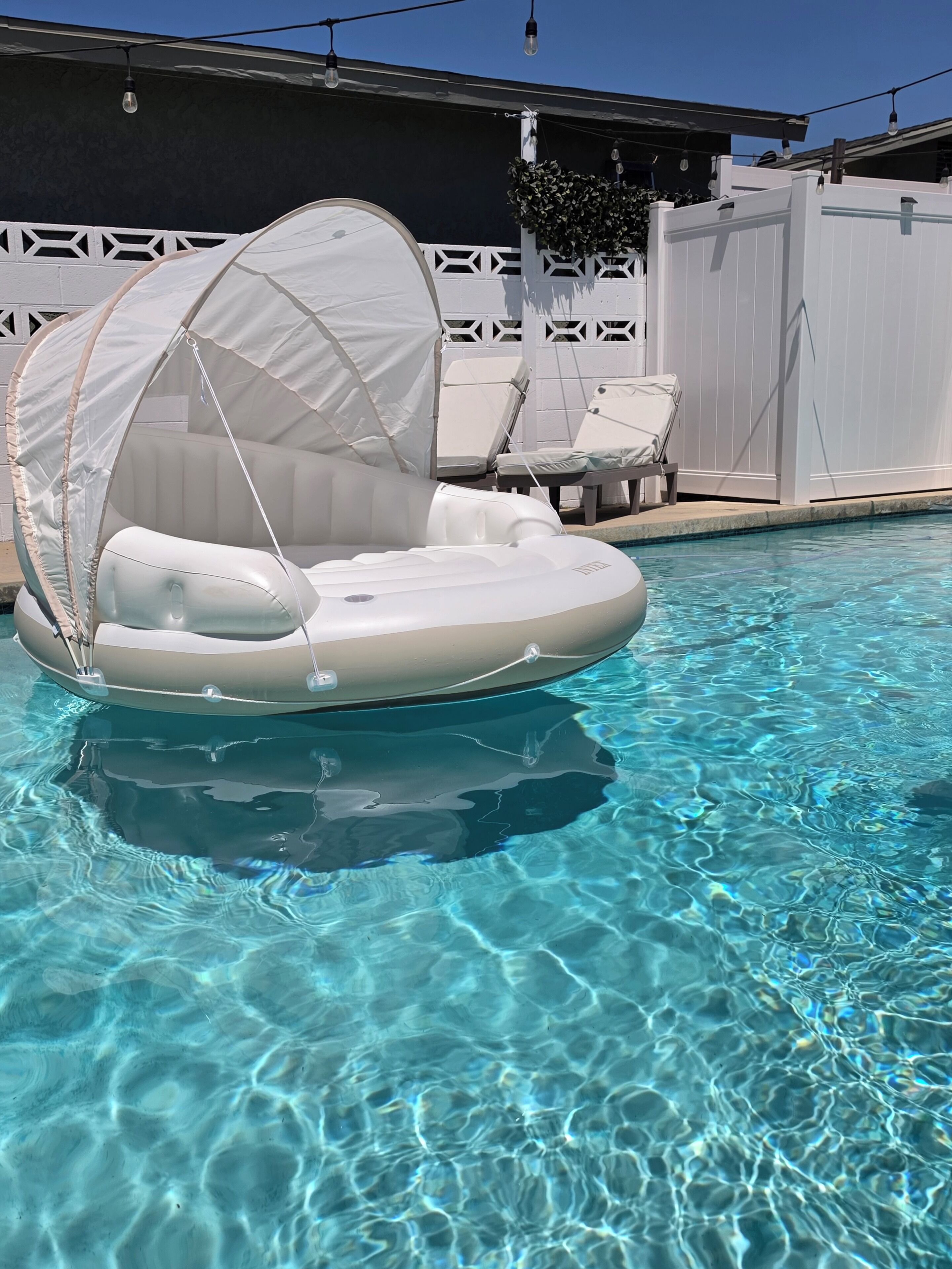 A clear swimming pool with a floating raft and lounge chairs.