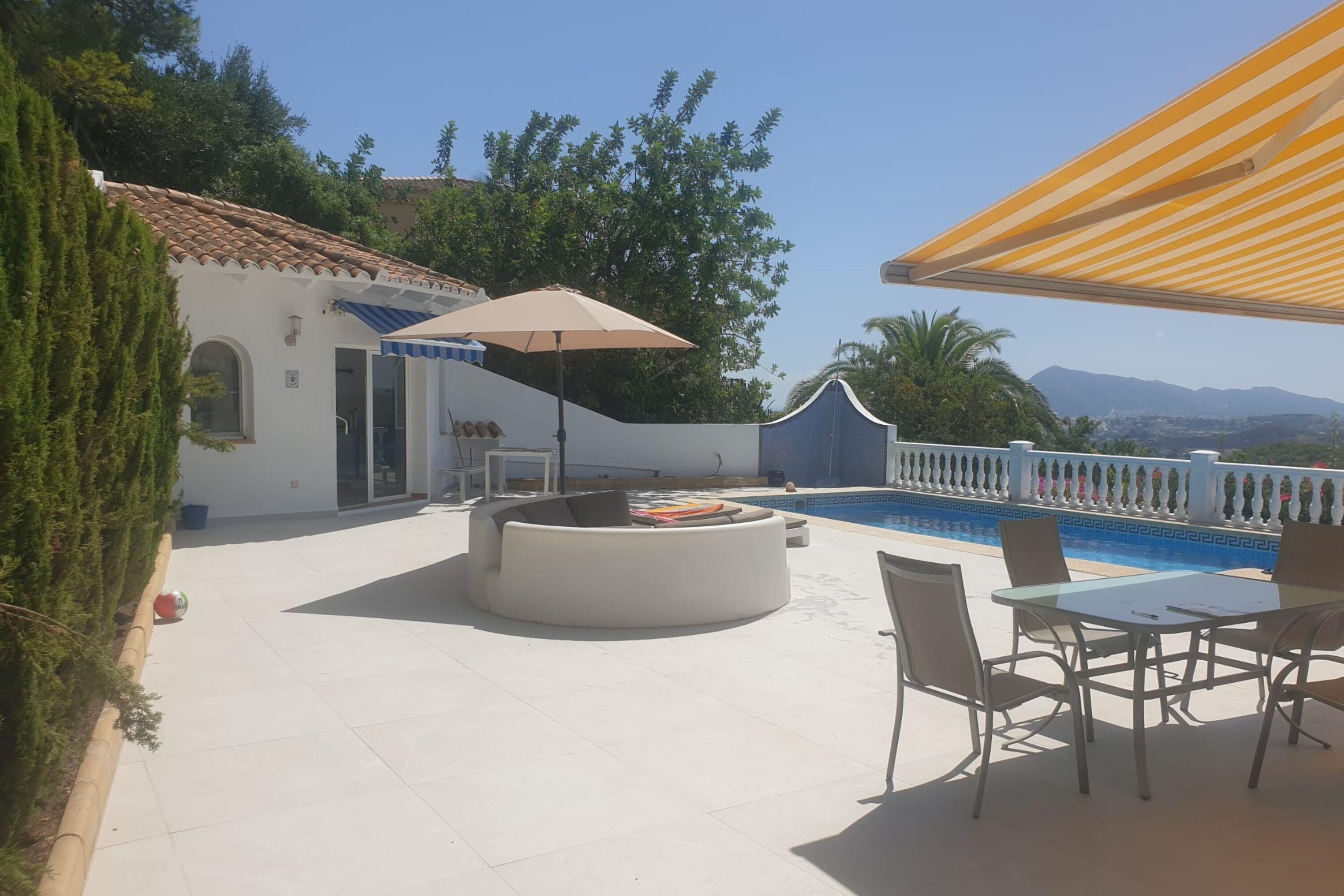 A patio with a pool, outdoor seating, and a view of the mountains.