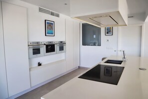 Eine moderne Küche mit eingebauten Backöfen, einer zentralen Kochinsel und einem Fenster.