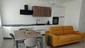 Et moderne køkken med hvide skabe, et træspisebord og en gul sofa.