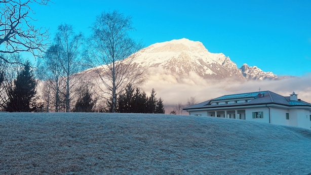 Et sneklædt landskab med et bjerg i baggrunden og et hus i forgrunden.