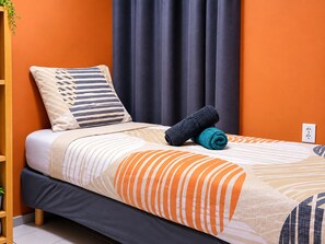 Een bed met gestreept beddengoed, een opgerolde handdoek en een kussen.