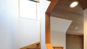 Een houten trap met een dakraam, leidend naar een kamer met een visgraatmotief wand en een kast.