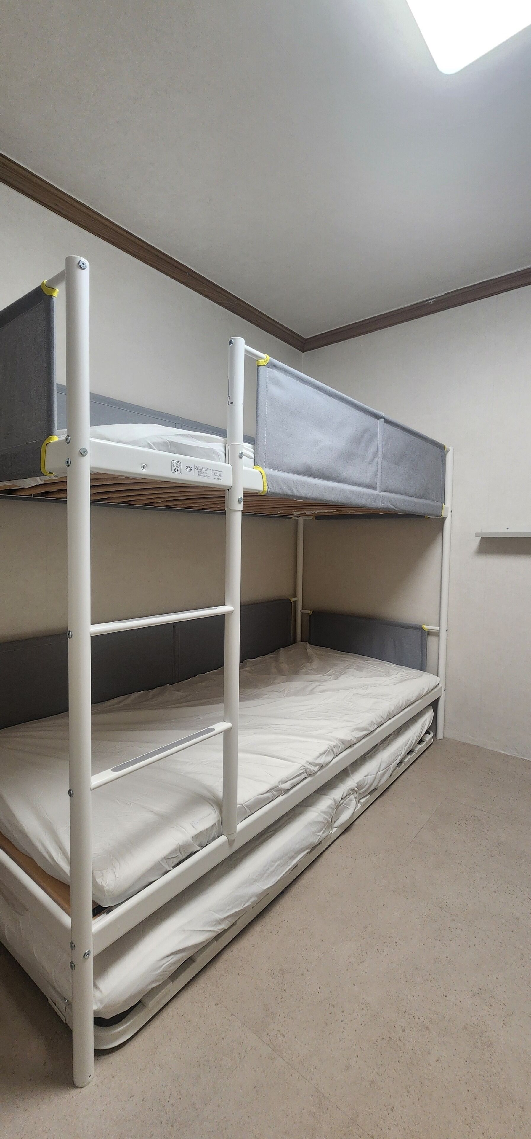 A bunk bed with a headboard and footboard, a window with blinds, and a plain wall.