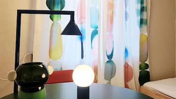 A round table with a lamp, a decorative object, and a curtain with a colorful pattern.