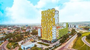 A modern high-rise building with a unique facade, surrounded by a cityscape. - Modern 3bdr Apt at Villaggio - Rooftop Pool & Skybar (Accra)