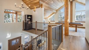 A spacious interior with a high ceiling, wooden beams, and large windows offering views of trees. - Cle Elum Sunrise Lodge (Cle Elum)