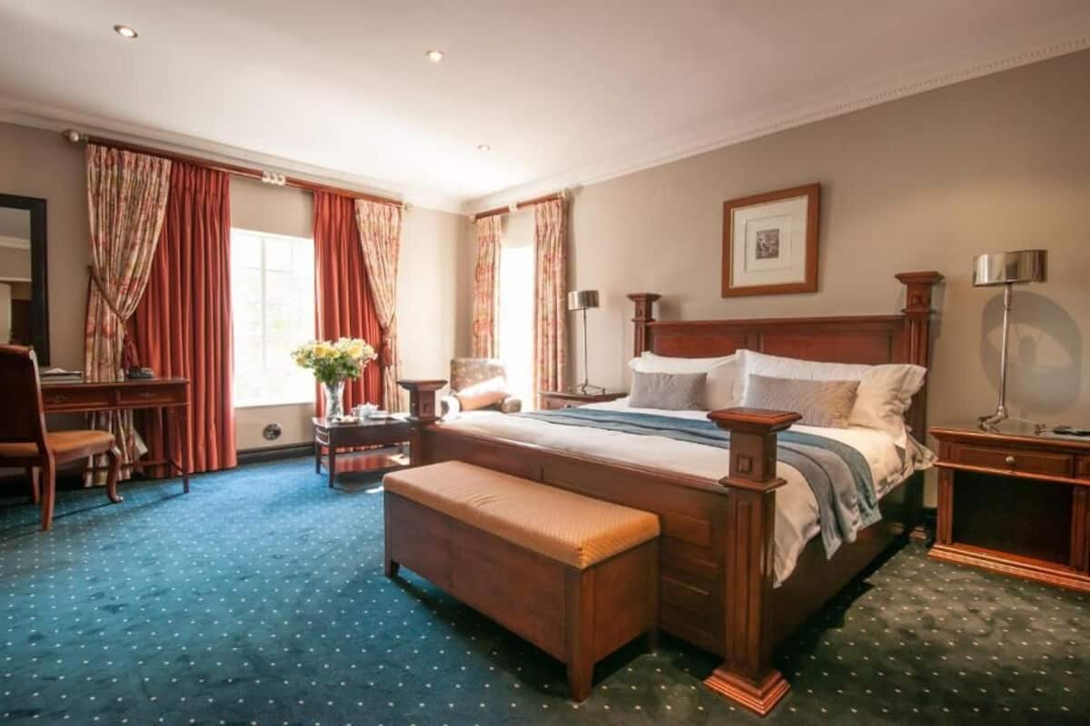 A spacious bedroom with a large bed, a wooden bench, a desk, and a chair.