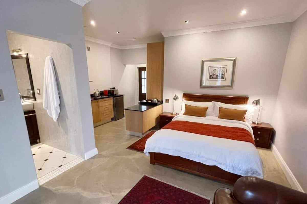 A bedroom with a large bed, a nightstand, a bedside table, a mirror, and a red rug.