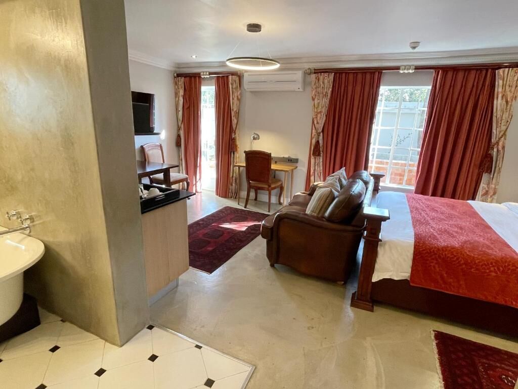 Una habitación de hotel con cama, sofá, escritorio y baño.