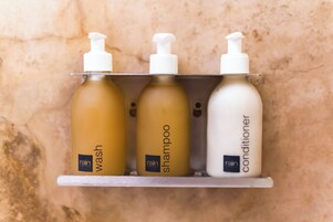 Three bottles of 'rain' shampoo and conditioner on a shelf.