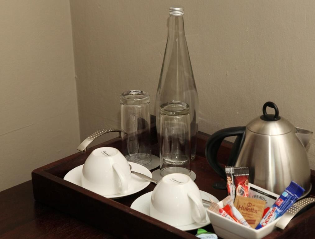 A tray with a coffee pot, cups, and a box of snacks.