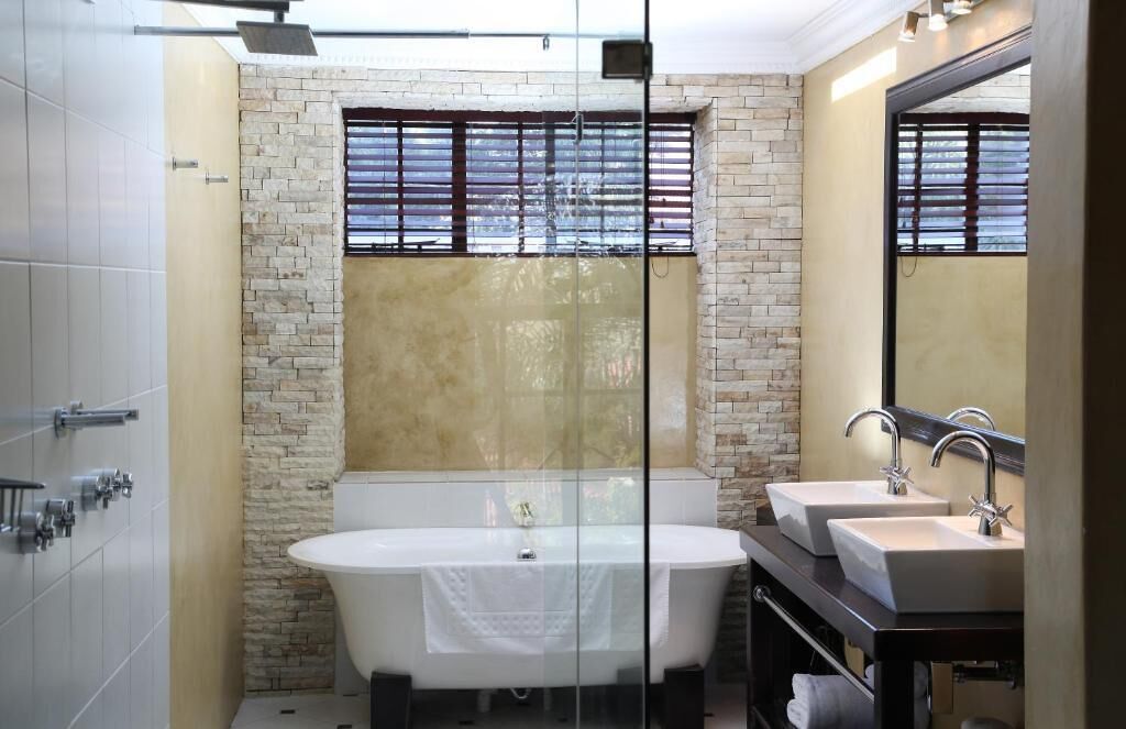 Ein modernes Badezimmer mit einer freistehenden Badewanne, zwei Waschbecken und einem großen Spiegel.
